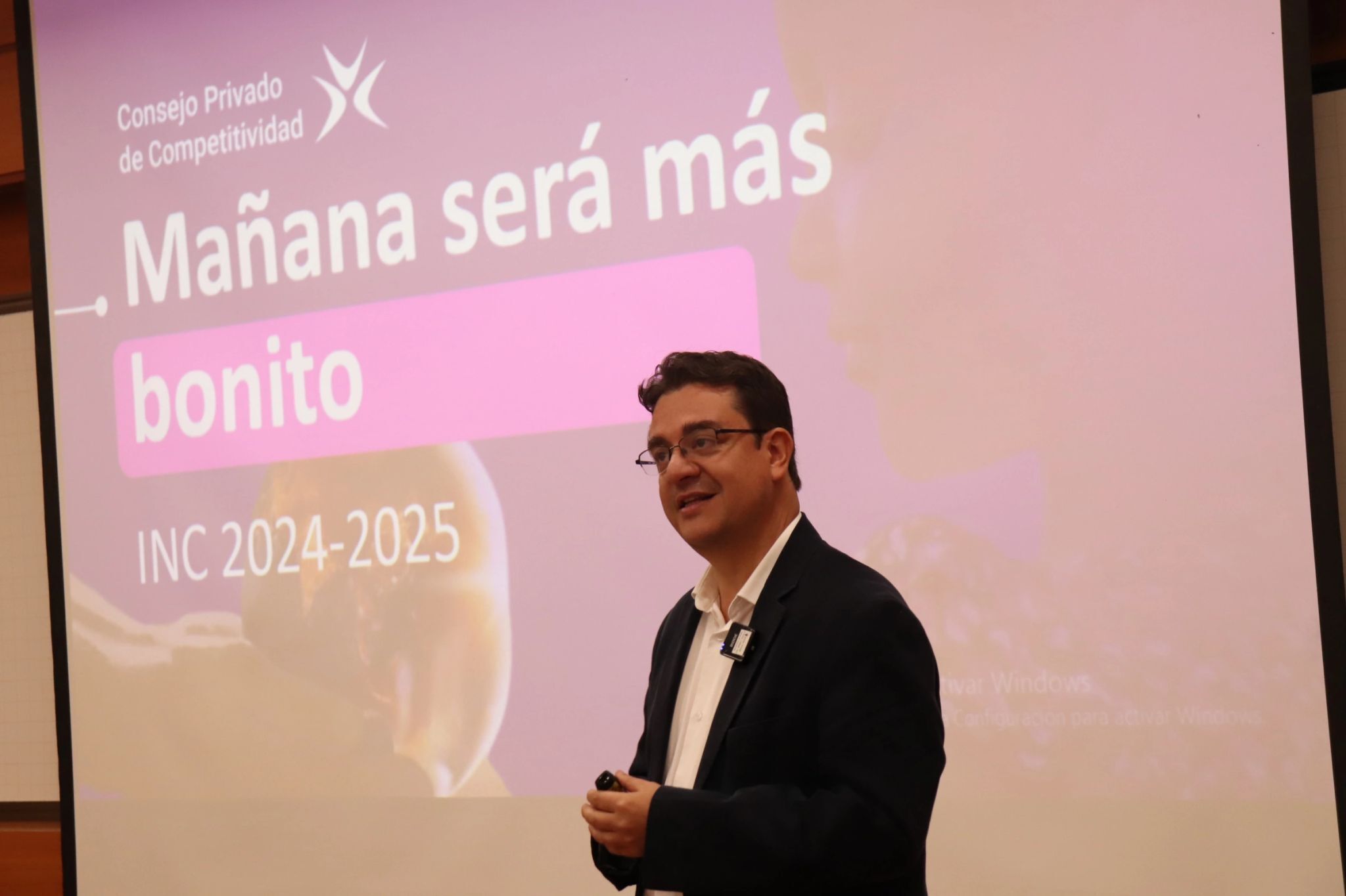 Persona dando una presentación en un auditorio con proyección al fondo